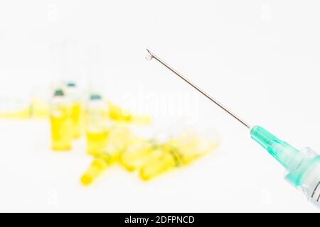 Verschwommene Glasampullen mit hypodermischer Spritze für Covid-Impfstoff, UK-Cunding Covid, V Day, Coronavirus-Impfstoff & scharfe Spritzenspitze auf neutralem B/Boden Stockfoto