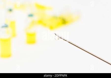 Verschwommene Glasampullen mit hypodermischer Spritze für Covid-Impfstoff, UK-Cunding Covid, V Day, Coronavirus-Impfstoff & scharfe Spritzenspitze auf neutralem B/Boden Stockfoto