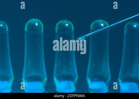 Verschwommene Glasampullen mit hypodermischer Spritze für Covid-Impfstoff, UK-Cunding Covid, V Day, Coronavirus-Impfstoff & scharfe Spritzenspitze auf neutralem B/Boden Stockfoto