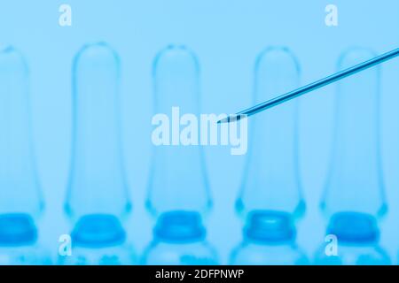 Verschwommene Glasampullen mit hypodermischer Spritze für Covid-Impfstoff, UK-Cunding Covid, V Day, Coronavirus-Impfstoff & scharfe Spritzenspitze auf neutralem B/Boden Stockfoto