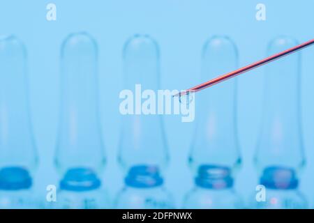 Verschwommene Glasampullen mit hypodermischer Spritze für Covid-Impfstoff, UK-Cunding Covid, V Day, Coronavirus-Impfstoff & scharfe Spritzenspitze auf neutralem B/Boden Stockfoto