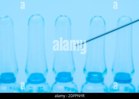 Verschwommene Glasampullen mit hypodermischer Spritze für Covid-Impfstoff, UK-Cunding Covid, V Day, Coronavirus-Impfstoff & scharfe Spritzenspitze auf neutralem B/Boden Stockfoto