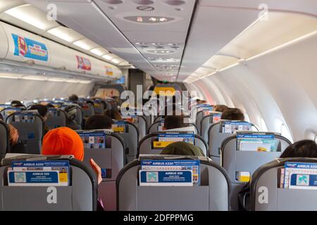 Voller Passagiere auf ihren Sitzen in einem startbereiten Airbus A320-Flugzeug. Keine leeren Sitzintervalle vor den Maßnahmen von Covid-19. Stockfoto