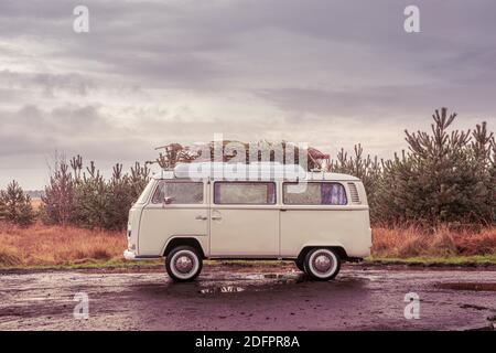 Vintage-Wohnmobil mit frisch geschnittenem Weihnachtsbaum auf dem Dach. Stockfoto