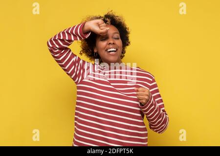 Müde afrikanische Frau nach dem Nickerchen dehnen. Studio auf gelber Wand. Stockfoto