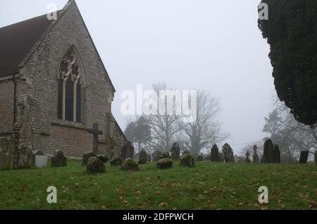 St. George's Church Gebäude und Friedhof an einem nebligen Tag im Winter, Crowhurst, Sussex, England, Großbritannien Stockfoto