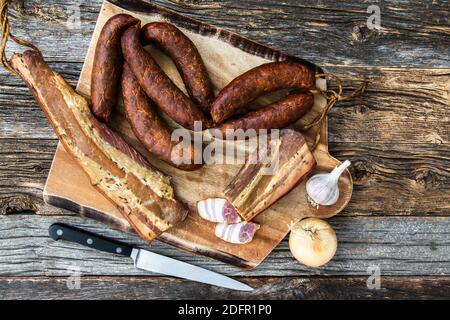 Traditionelle Tischansicht aus der Slowakei mit hausgemachten Speck Und Würstchen auf rustikalem Holzhintergrund Stockfoto