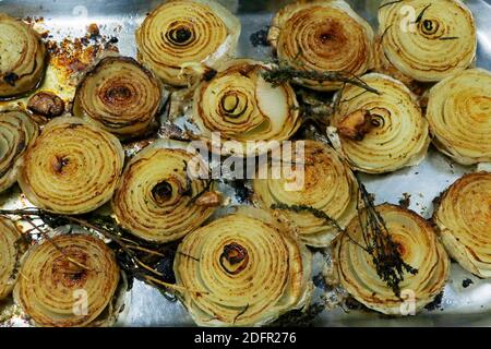 Gegrillte halbe weiße Zwiebeln mit Kräutern auf einem Metalltablett Stockfoto