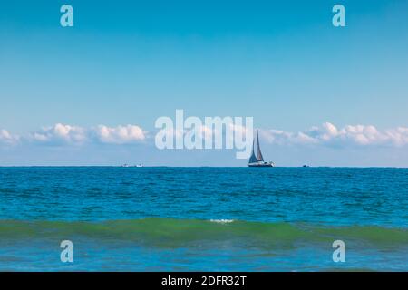 Meer und Segeln Wind Boot. Segelboot über blauen Wellen und sonnigen Himmel Stockfoto