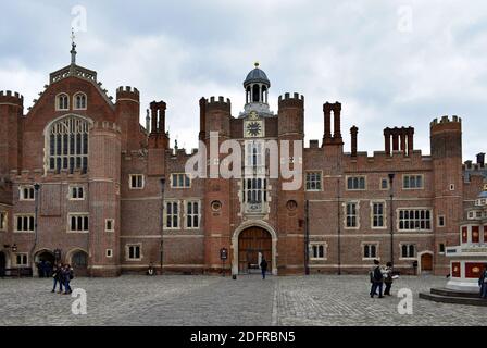 Schulkinder schlendern durch den Base Court im Hampton Court Palace in Richmond, London. Die große Halle und der Uhrenturm sind von den Kopfsteinpflaster aus zu sehen. Stockfoto