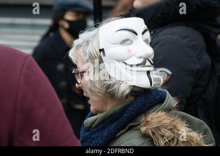 Manchester Piccadilly Gardens 6. Dez 2020: Eine grauhaarige Dame trägt eine Guy Fawkes oder Anonymous Maske auf dem Hinterkopf bei der Anti-Lockdown-Versammlung Stockfoto