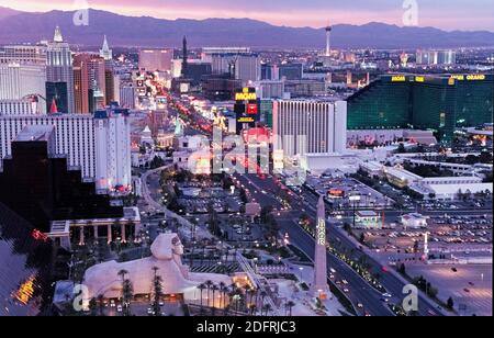 Ein Luftbild bei Sonnenuntergang zeigt die hellen Lichter der gehobenen Resort-Hotels und Casinos, die den Strip säumen, der der Spitzname für den weltberühmten 4.3 Meilen (6.8 Kilometer) Abschnitt des lebhaften Las Vegas Boulevard in Las Vegas, Nevada, USA ist. Dieses berüchtigte Wüstenziel, das für seine Glücksspiele und seine guten Zeiten bekannt ist, wurde in den 1940er Jahren mit seinem ersten Hotel/Casinos entlang des Strip zum Leben erweckt. In diesen Tagen leuchten elektronische Werbetafeln Tag und Nacht in Themenresorts, die ihre opulenten Showrooms mit namensreicher Unterhaltung annoncieren, die helfen, Millionen von Touristen jährlich nach Las Vegas anzuziehen. Stockfoto