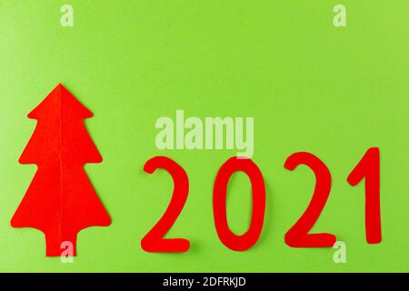 Neujahrskonzept 2021. Weihnachtsbaum 2021 auf grünem Hintergrund. Roter Neujahrsbaum aus Papier. Draufsicht Stockfoto