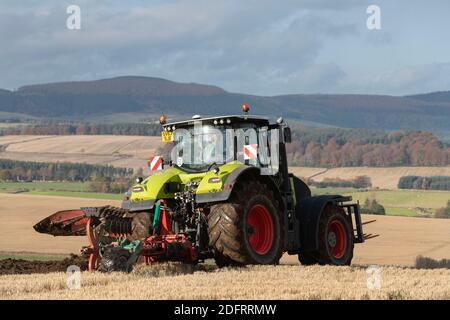 Ein Claas Axion 940 Traktor und Kverneland Variomat Wendepflug Arbeiten auf Farmland in Aberdeenshire mit den Menaway Hills in Die Entfernung Stockfoto