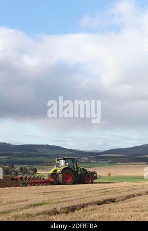 Ein Blick über Farmland in Aberdeenshire Richtung Suie mit Ein Claas Axion 940 Traktor und ein Kverneland Variomat Reversible Pflug im Vordergrund Stockfoto