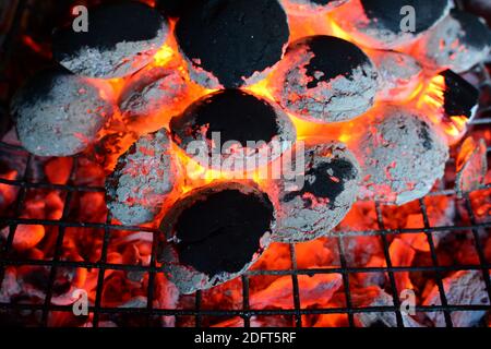 Ember auf Grill, Stapel brennender Kohle unter und auf Grill, Vorbereitung für Grill fast fertig, horizontale Ausrichtung, Nahaufnahme Stockfoto