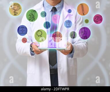 Männlicher Arzt mit Tablet-Computer auf grauem Hintergrund. Konzept moderner Technologien in der Medizin Stockfoto