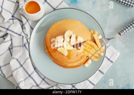 Teller mit leckeren Bananenpfannkuchen mit Honig auf dem Tisch Stockfoto