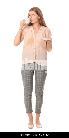 Junge Frau mit Flecken auf ihrem T-Shirt trinkt Kaffee auf Weißer Hintergrund Stockfoto