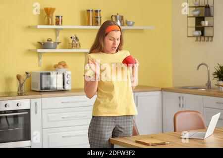 Gestresste junge Frau mit Kaffeeflecken auf ihrem T-Shirt in Küche Stockfoto