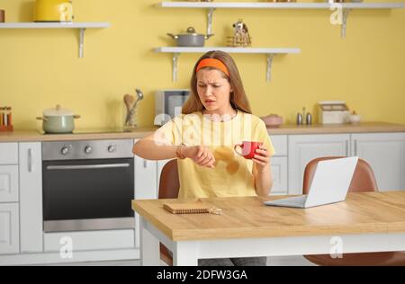 Gestresste junge Frau mit Kaffeeflecken auf ihrem T-Shirt in Küche Stockfoto