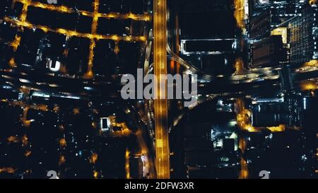 Top down Nacht Stadtverkehr Autobahn an Laternen Lichter mit Stadtbild Luftbild. Downtown Dämmerung beleuchten städtische Straße mit modernen Architektur Gebäuden, Wolkenkratzern. Filmische philippinische Stadt Stockfoto