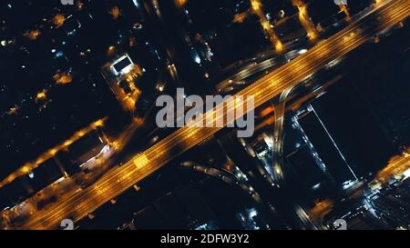 Top down der Nachtbeleuchtung Verkehrsautobahn bei beleuchteten Straßen Antenne. Städtische philippinische Stadtlandschaft an der Straße von Laternen beleuchtet. Downtown Moderne Architektur: Wolkenkratzer Gebäude. Filmische Stadt der Dämmerung Stockfoto