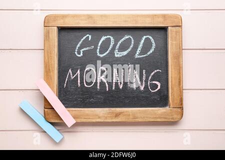 Bunte Kreiden und Kreidetafel mit Text GUTEN MORGEN auf Holz Hintergrund Stockfoto