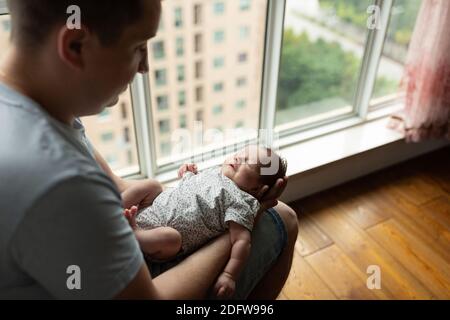 Junge kaukasische Vater hält neugeborenes Mädchen. Männlicher Mann Eltern und Kind Tochter. Authentischer Lifestyle dokumentarischer Moment. Alleinstehend Vater Familienleben Stockfoto