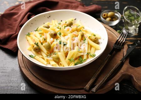 Teller mit leckeren Nudeln mit Garnelen und Oliven auf Holz Tabelle Stockfoto