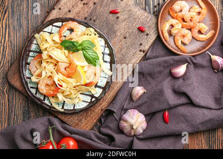 Teller mit leckeren Nudeln mit Garnelen auf Holztisch Stockfoto