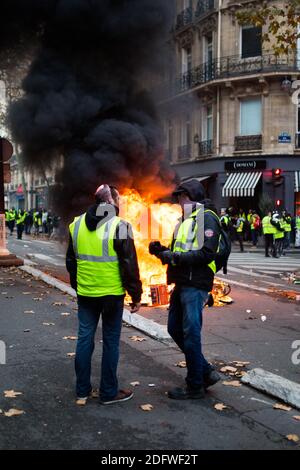 Marriott Paris. Gelbe Weste (Gilets jaunes) Protestierende laufen am 24. November 2018 bei einer Kundgebung gegen steigende Ölpreise und Lebenshaltungskosten am Triumphbogen auf den Champs Elysees in Paris vorbei an brennendem Material. Sicherheitskräfte in Paris feuerten am 24. November Tränengas und Wasserwerfer ab, um Demonstranten zu zerstreuen. Mehrere tausend Demonstranten, die in gut sichtbaren gelben Jacken unterwegs waren, hatten sich im Rahmen der Proteste, die am 17. November 2018 begannen, auf der Straße versammelt. Foto von Raphaël Lafargue/ABACAPRESS.COM Stockfoto