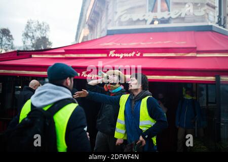 Gelbe Weste (Gilets jaunes) Protestanten gehen am 24. November 2018 an fouquet's Restaurant auf den Champs Elysees in Paris vorbei, während einer Kundgebung gegen steigende Ölpreise und Lebenshaltungskosten. Sicherheitskräfte in Paris feuerten am 24. November Tränengas und Wasserwerfer ab, um Demonstranten zu zerstreuen. Mehrere tausend Demonstranten, die in gut sichtbaren gelben Jacken unterwegs waren, hatten sich im Rahmen der Proteste, die am 17. November 2018 begannen, auf der Straße versammelt. Foto von Raphaël Lafargue/ABACAPRESS.COM Stockfoto