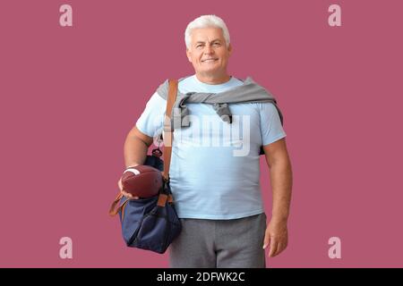 Sportlicher Senior mit Tasche und Rugby Ball in Farbe Hintergrund Stockfoto