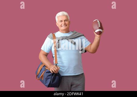 Sportlicher Senior mit Tasche und Rugby Ball in Farbe Hintergrund Stockfoto