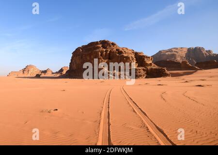 Wadi Rum Valley im südlichen Jordanien mit interessanten geologischen Gesteinsformationen. Auch bekannt als das Tal des Mondes. Autospuren im roten Sand. Stockfoto