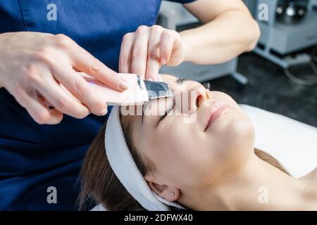 Junge hübsche dunkelhaarige Frau, die auf der Couch liegt und Behandlungen in Schönheitssalons erhält. Ultraschallreinigung. Hardware-Kosmetik. Schönheit s Stockfoto