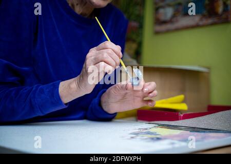 Alter, Ruhestand, Kreativität, Phantasie und Kunst. Kreatives Arbeiten. Kaukasische reife weibliche Farben Bild auf Leinwand mit Ölfarbe und Pinsel zu Hause Dur Stockfoto