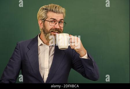 Optimistisches Konzept. Angenehmer Schluck. Kaffeepause und Entspannung. Mittagszeit für Lehrer. Kaffeesüchtig. Energieaufladung für den ganzen Tag. Koffeindosis. Lehrer in der Brille trinken Kaffee Kelkboard Hintergrund. Stockfoto