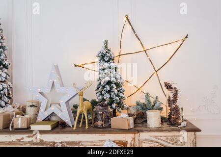 Weihnachtsdekoration auf alten Vintage alte Kommode Kommode. Handarbeit Handwerk Geschenke, Kerzen und ein Baum im Hintergrund. Stockfoto