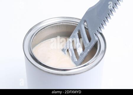 Ein Mann, der weiße Farbe in einer Dose auf weißem Hintergrund rührt. Renovierungskonzept. Stockfoto