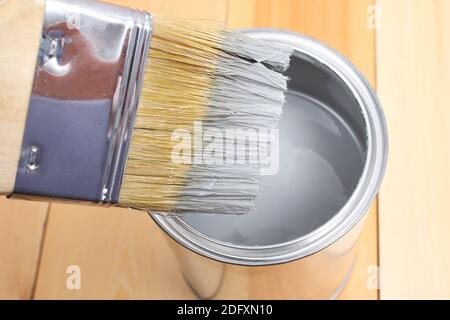 Pinsel mit Dose malen in der Hand. Ein Mann malt Holzbretter mit einem grauen Pinsel. Stockfoto
