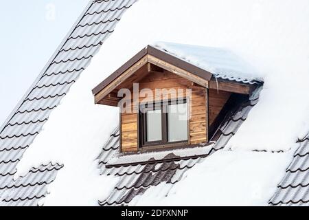 Nahaufnahme einer Mansarde Kunststoff-Fenster auf einem Landhaus, das Dach ist mit Schnee bedeckt Stockfoto