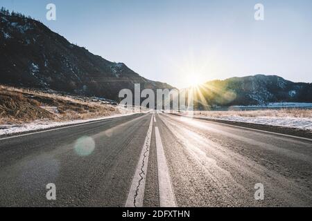 Winter Hintergrund des Vordergrunds der Straße mit Schnee und Eis bedeckt. Im Hintergrund die arktische Landschaft der Berge mit dem schönen blauen Himmel. Stockfoto