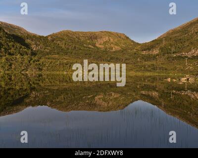 Blick auf den schönen See Storvatnet in der Nähe von Tromsø im Norden Norwegens mit Ufer, Wald und Berge in der ruhigen klaren Wasser reflektiert. Stockfoto