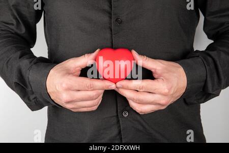 Mann, der das Symbol des Herzens am Körper hält. Gesundheitskonzept der inneren Organe. Symbol der Liebe. Stockfoto