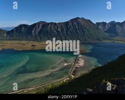 Atemberaubender Panoramablick auf Fjord Grunnførfjorden mit Straßendamm und türkisfarbenem seichtem Wasser und Bergen im Hintergrund am sonnigen Sommertag. Stockfoto