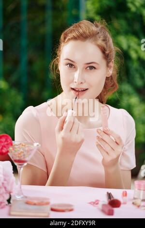 Junge Frau Auftragen von Lippenstift Stockfoto