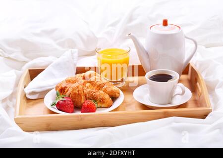 Frühstück im Bett. Tablett mit Tasse Kaffee und Croissants Stockfoto