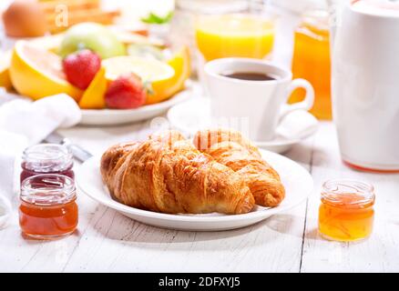 Frühstückstisch mit Croissants, Kaffee, Orangensaft, Toast und Obst Stockfoto